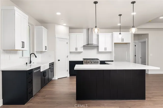 a kitchen with stainless steel appliances a sink a stove a refrigerator and white cabinets