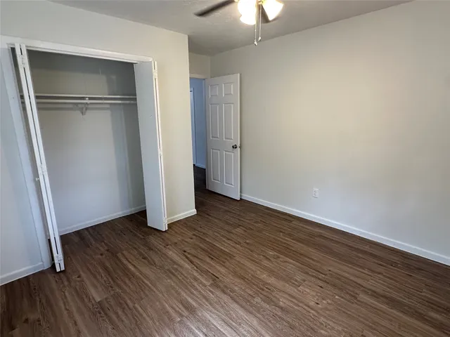 an empty room with wooden floor closet and windows
