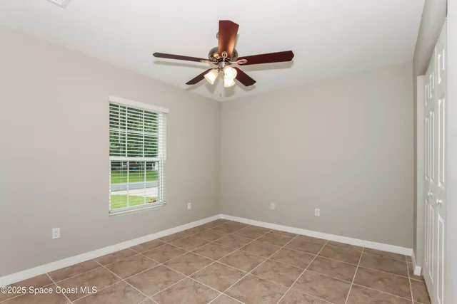an empty room with windows and fan