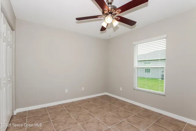 an empty room with windows and fan