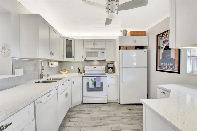 a kitchen with stainless steel appliances granite countertop a refrigerator sink and white cabinets
