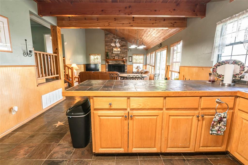 698 Storey Road Nocona, TX 76255 - Photo 34 of 34 Kitchen with open floor plan, wainscoting, wooden walls, wooden ceiling, and a stone fireplace