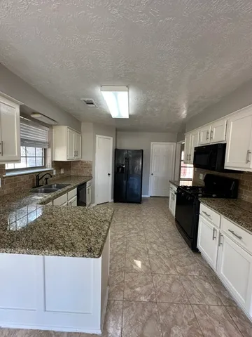 a large kitchen with stainless steel appliances granite countertop a large counter top and a stove top oven