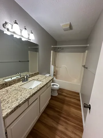 a bathroom with a granite countertop sink toilet and shower