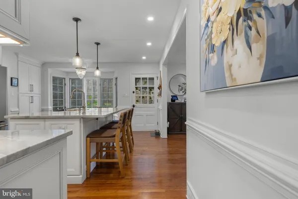 a kitchen with stainless steel appliances granite countertop a dining table chairs stove refrigerator and cabinets