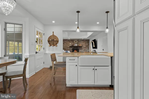 a kitchen with stainless steel appliances kitchen island granite countertop a dining table chairs and white cabinets