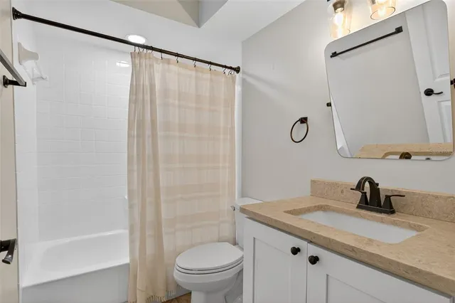 a bathroom with a granite countertop sink a toilet and shower