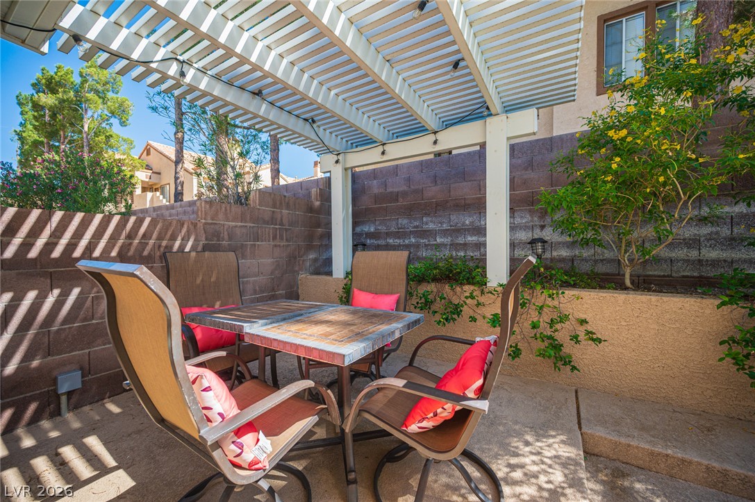 718 Rusty Spur Drive Henderson, NV 89014 - Photo 22 of 50 A tranquil patio with a slatted pergola invites comfortable outdoor dining and relaxation.