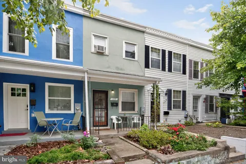 front view of a brick house with potted plants and a bench