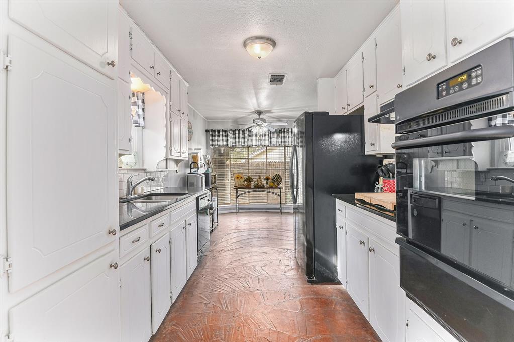 6608 Swanee Court Watauga, TX 76148 - Photo 11 of 30 a kitchen with stainless steel appliances granite countertop a refrigerator a sink dishwasher a dining table and chairs with wooden floor