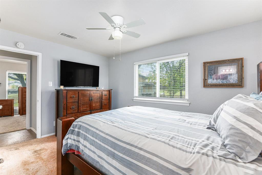 6608 Swanee Court Watauga, TX 76148 - Photo 20 of 30 a bedroom with a large bed a flat tv and a chandelier