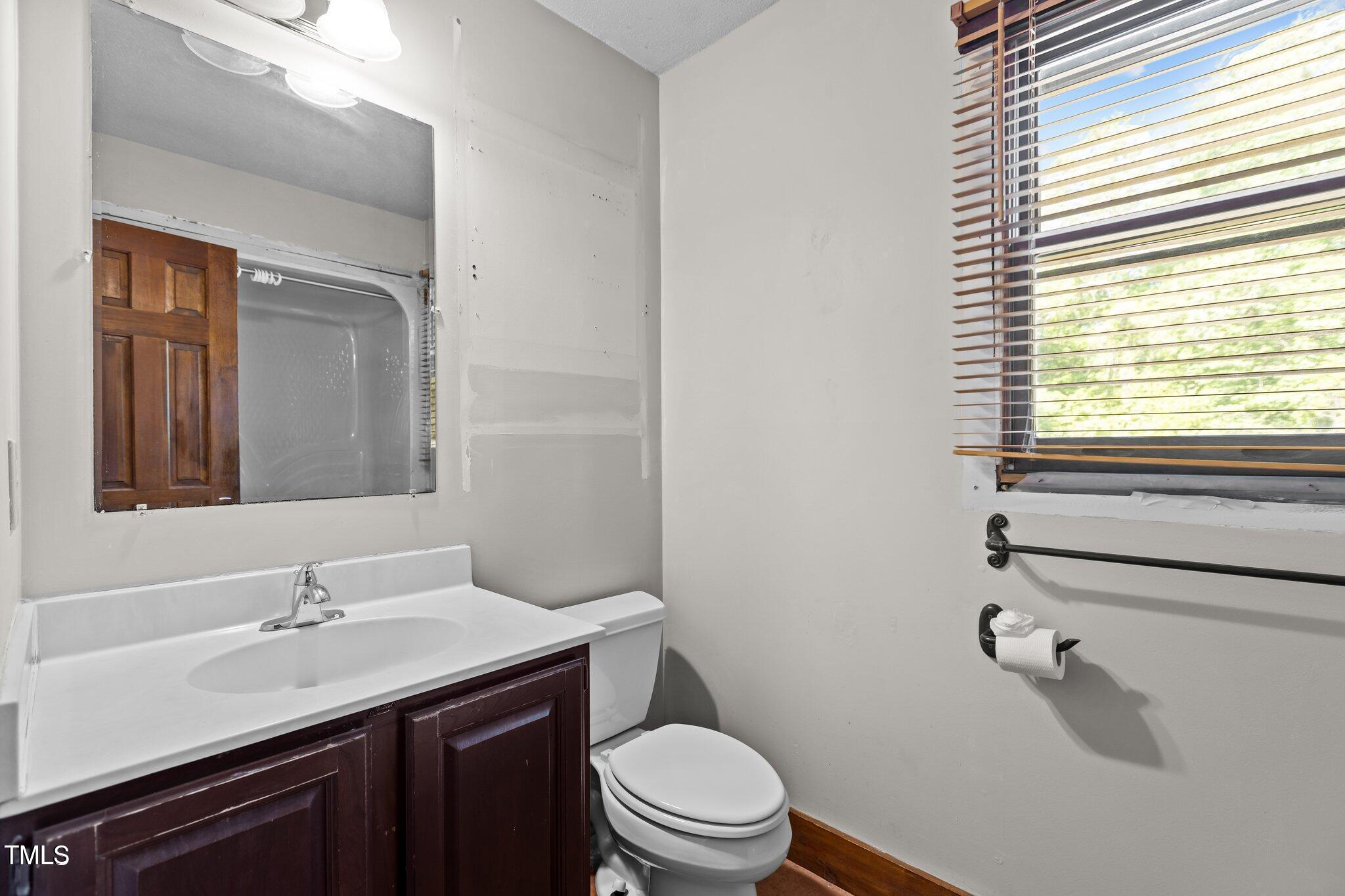 5900 Ebenezer Church Road Raleigh, NC 27612 - Photo 43 of 71 a bathroom with a toilet a sink a mirror a window and vanity