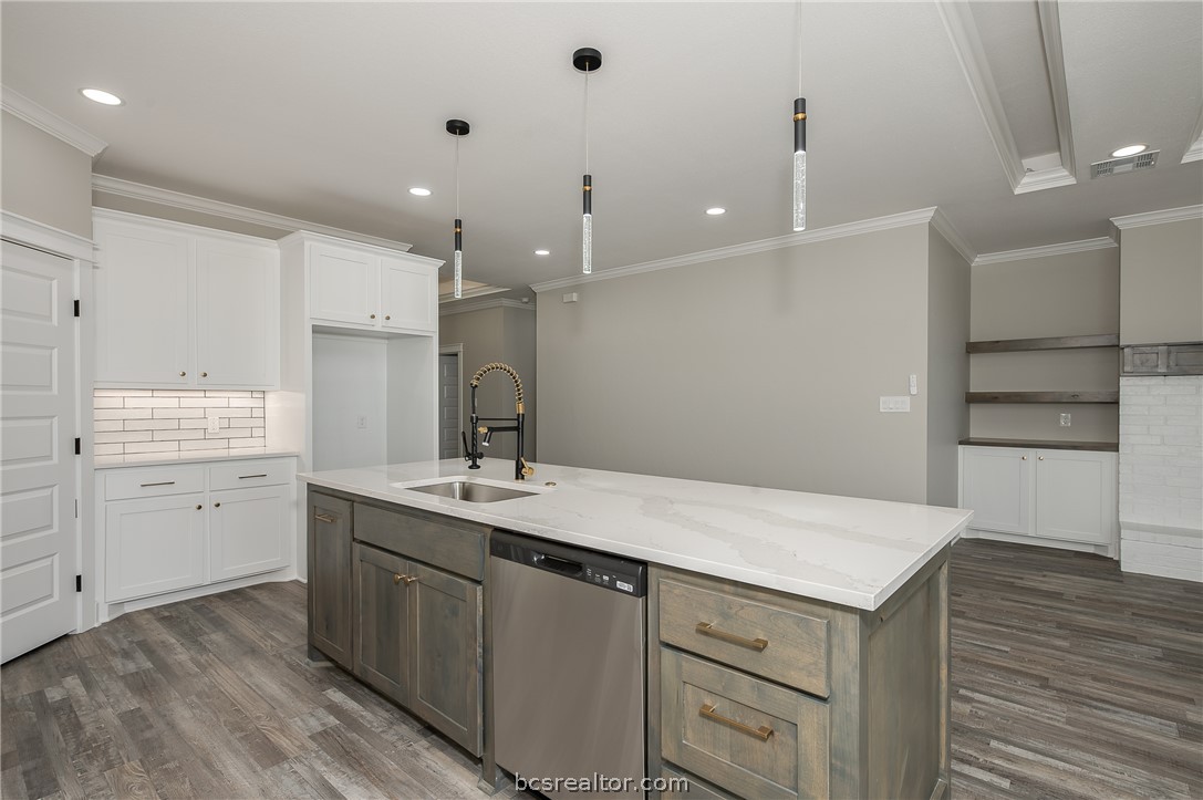 2908 GOLDBERG Drive Bryan, TX 77808 - Photo 22 of 44 Modern kitchen features: stainless steel appliances, quartz countertops, stained island, painted cabinets, decorative pendant lights, cabinet hardware, vinyl flooring, and tile backsplash.