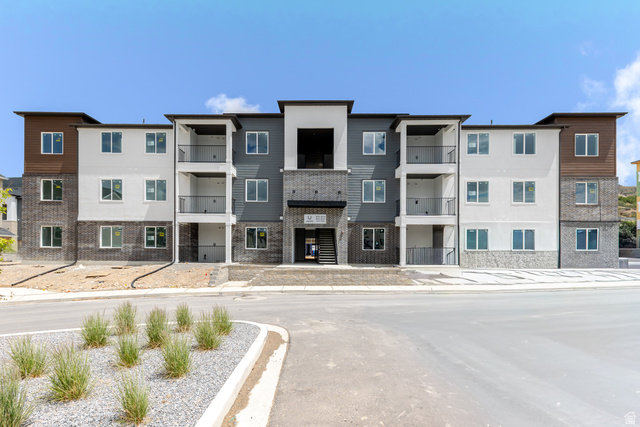 Contemporary multi-story building featuring a brick and siding facade with varied tones of white, grey, and brown