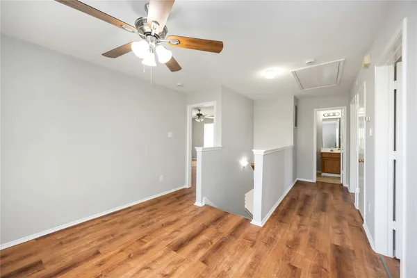 wooden floor in an empty room with a chandelier fan