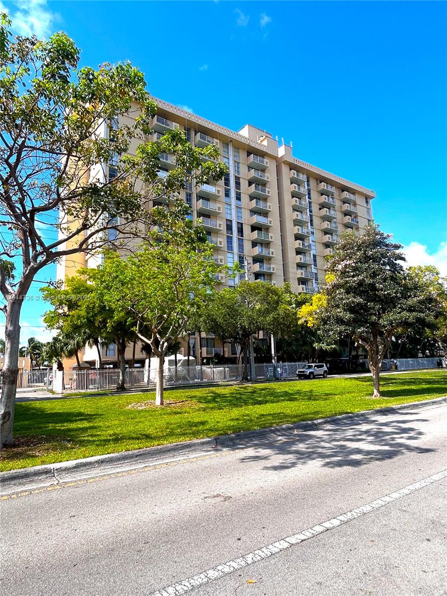 a view of a big building with a big yard and large trees