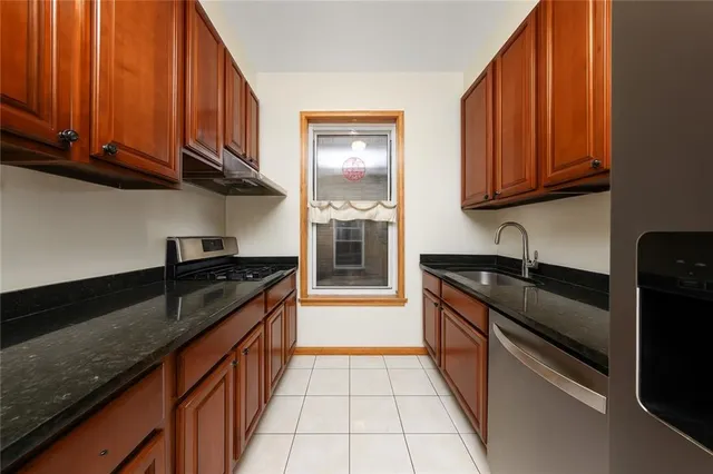 a kitchen with granite countertop stainless steel appliances a stove sink and cabinets
