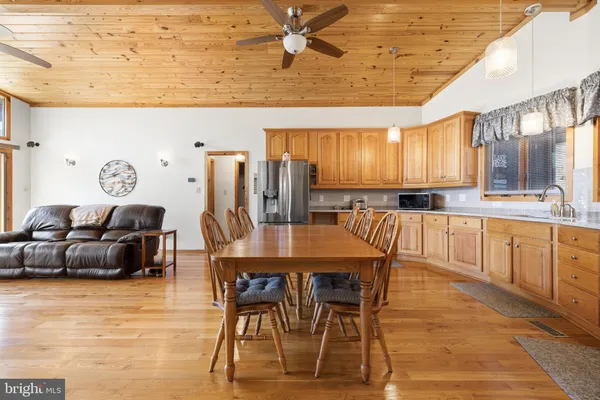 a kitchen with stainless steel appliances granite countertop a refrigerator a stove top oven a sink dishwasher and chairs with wooden floor
