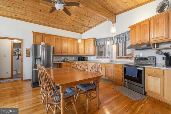 a kitchen with stainless steel appliances a refrigerator a sink dishwasher a stove and a dining table with wooden floor
