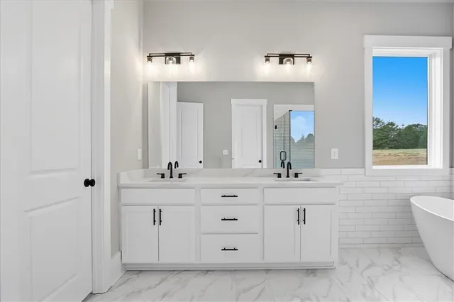 a spacious bathroom with a granite countertop sink mirror and bathtub