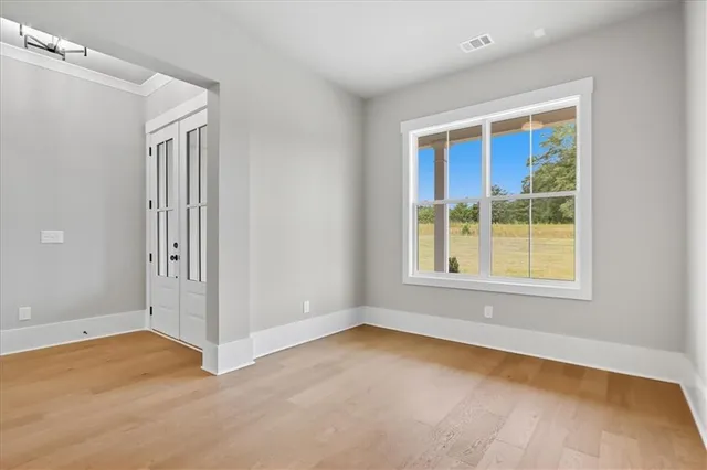 an empty room with wooden floor and windows