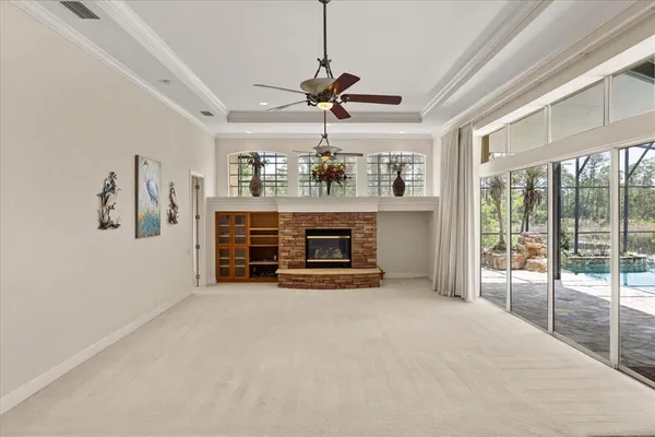 a view of a livingroom with a fireplace a chandelier fan and windows