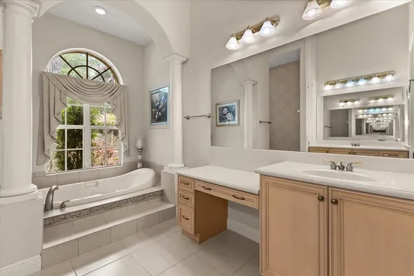a spacious bathroom with a sink a mirror and a bathtub next to a window
