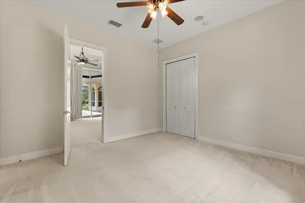 an empty room with a window and a chandelier fan
