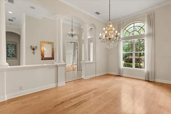 a view of a hallway with chandelier and wooden floor