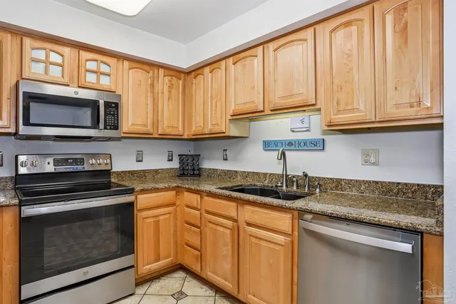 a kitchen with granite countertop cabinets stainless steel appliances a sink and window