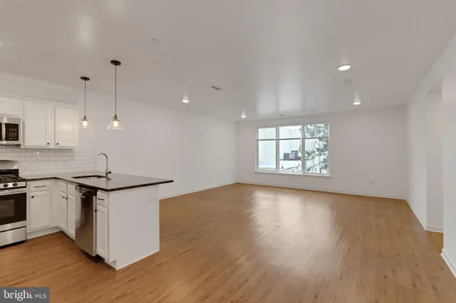 a kitchen with stainless steel appliances granite countertop a stove a sink and a large window