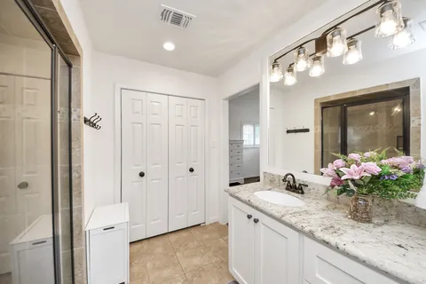 a bathroom with a granite countertop sink a large mirror and a shower