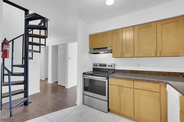a view of an empty room with wooden floor and windows