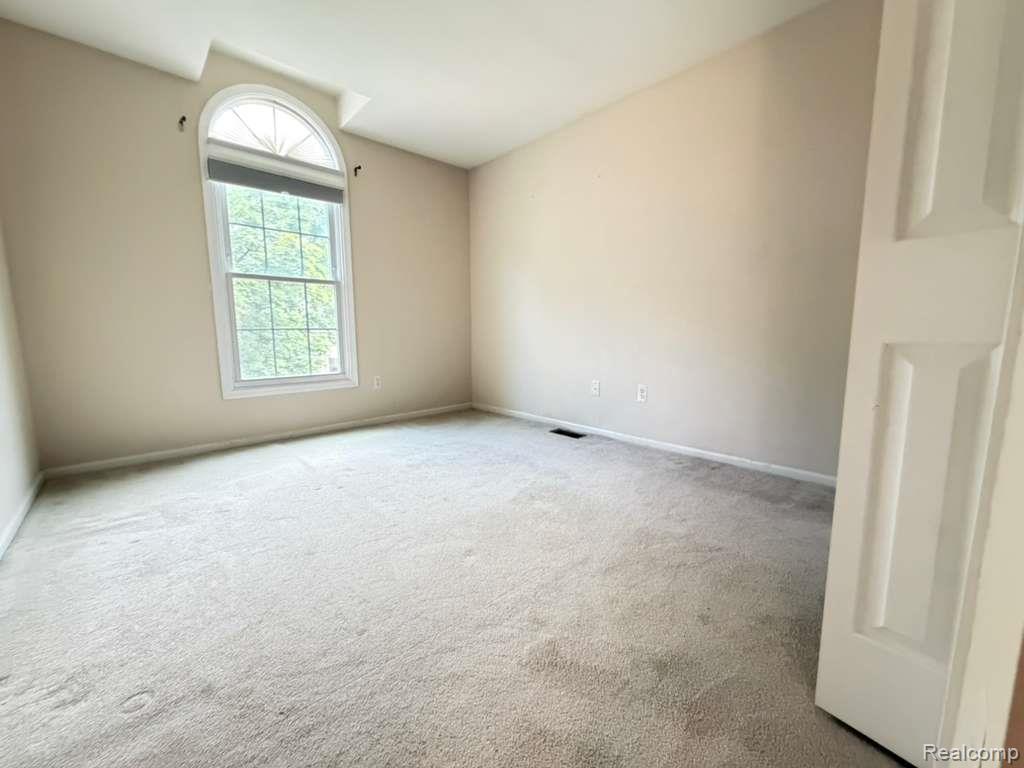 1154 Bluebird Drive Rochester, MI 48307 - Photo 20 of 34 Room featuring an arched transom window, light-toned carpeting, and neutral wall tones