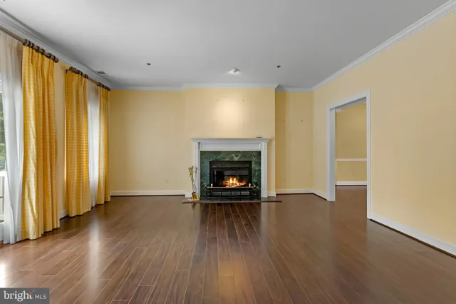 an empty room with wooden floor a fireplace and a window
