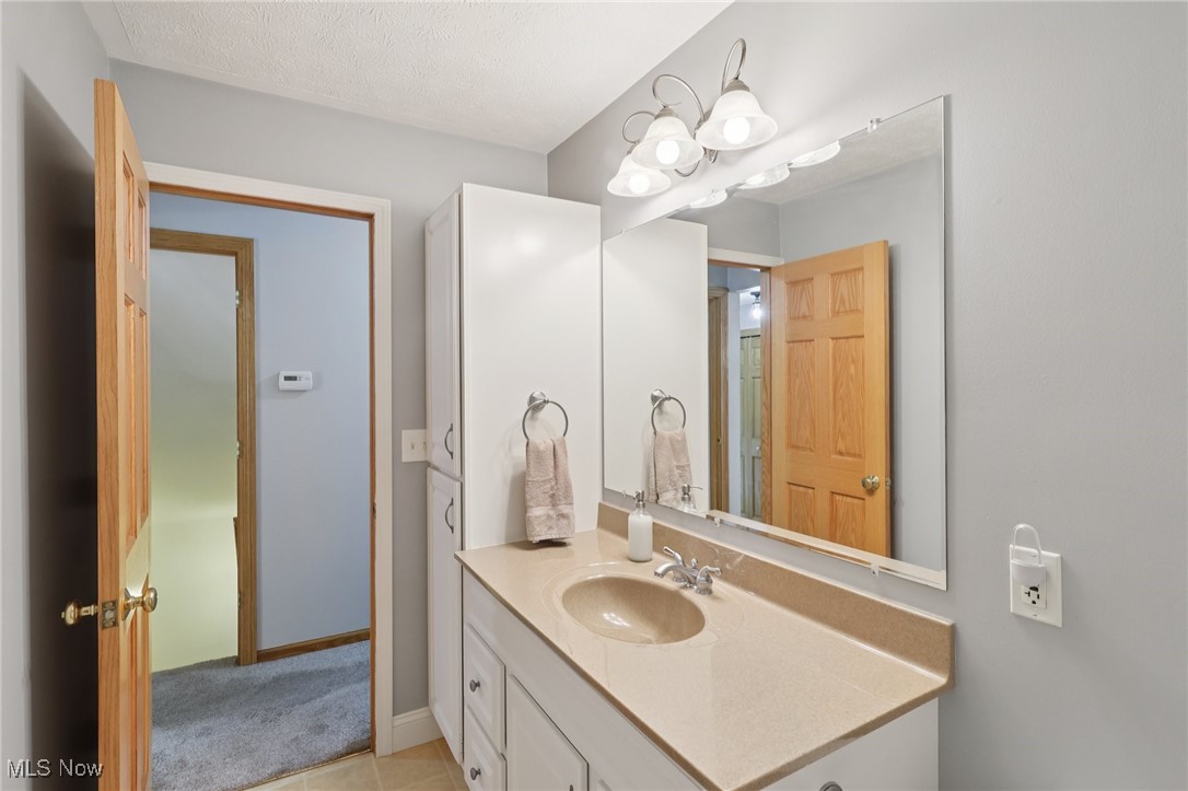 5877 Pearl Road Cleveland, OH 44130 - Photo 18 of 42 Bathroom featuring vanity, light tile patterned floors, and a textured ceiling
