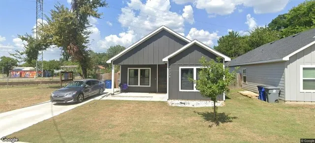 a front view of house with yard and trees in the background