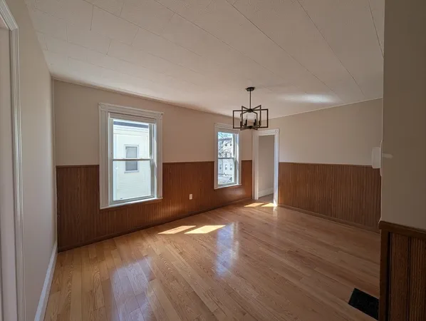 an empty room with wooden floor cabinet and windows