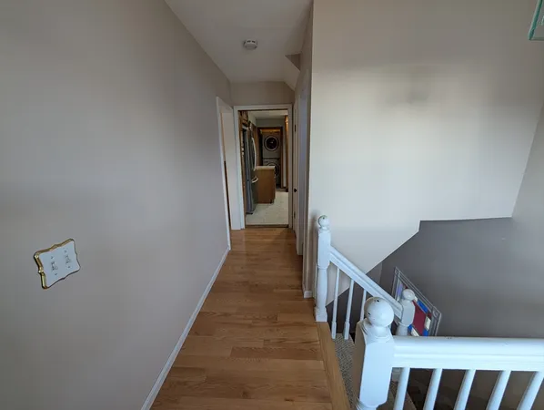 a hallway with wooden floor and stairs