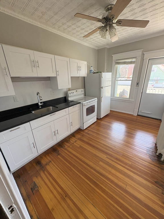 356 Springfield Street, Unit 1 Chicopee, MA 01013 - Photo 2 of 10 a kitchen with granite countertop wooden floors white cabinets and stainless steel appliances