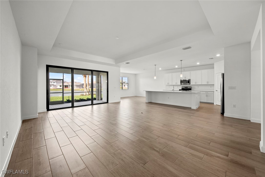 20446 Napa Loop Estero, FL 33928 - Photo 15 of 42 a view of an empty room with wooden floor and a kitchen