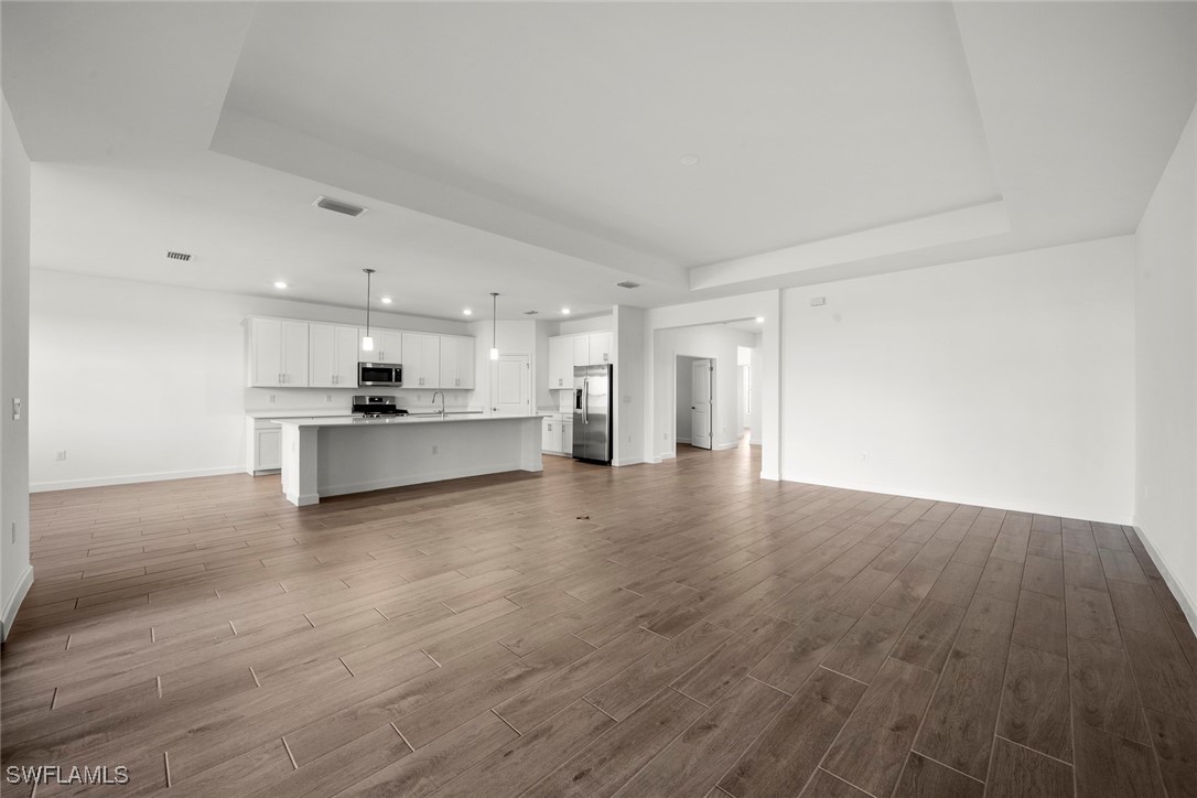 20446 Napa Loop Estero, FL 33928 - Photo 16 of 42 a view of an empty room with wooden floor and a kitchen
