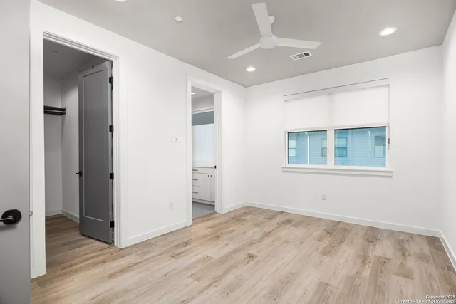 a view of empty room with wooden floor and fan