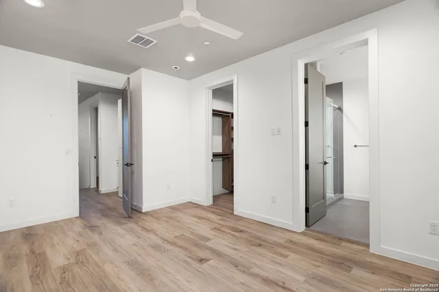an empty room with wooden floor and a ceiling fan
