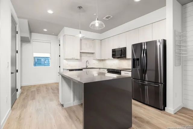 a kitchen with kitchen island a sink stainless steel appliances and cabinets