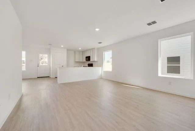 a view of a electric appliances in kitchen and empty room with wooden floor