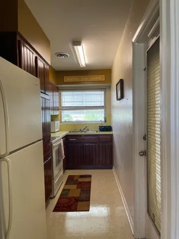 a kitchen with stainless steel appliances kitchen island granite countertop a refrigerator and a sink