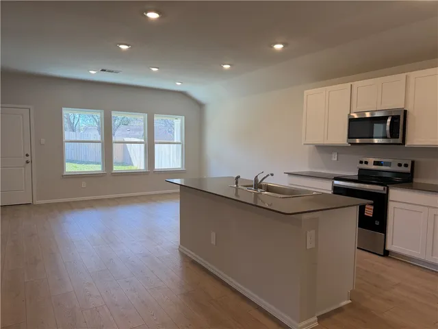 a kitchen with stainless steel appliances granite countertop a sink and a stove top oven