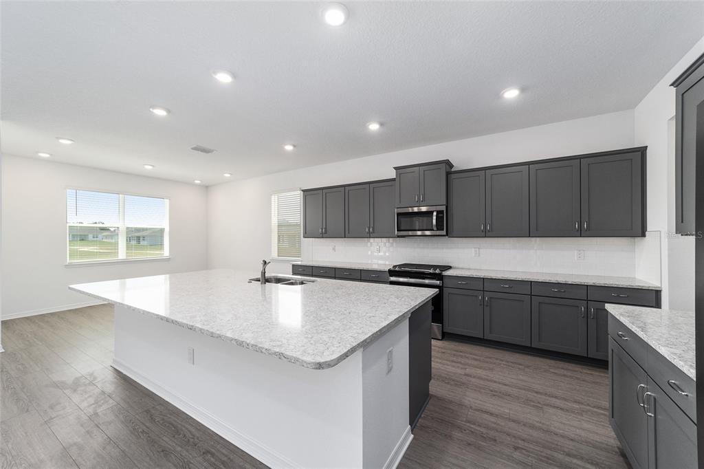 7232 Southwest 63rd Street Ocala, FL 34474 - Photo 17 of 54 a large kitchen with stainless steel appliances a large counter top a stove a sink a refrigerator and a cabinets