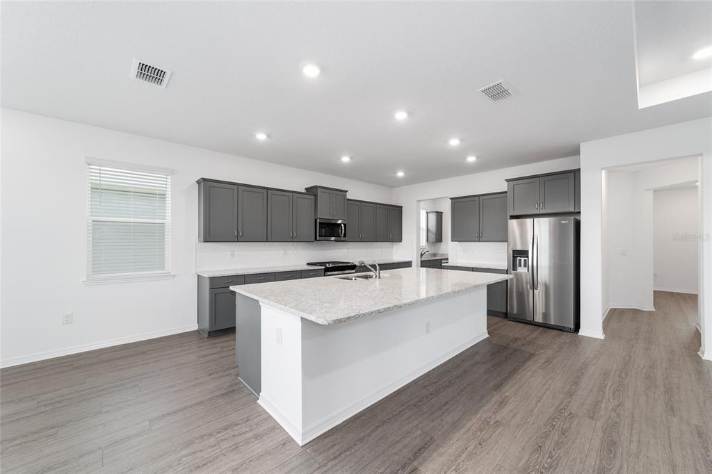 7232 Southwest 63rd Street Ocala, FL 34474 - Photo 19 of 54 a large kitchen with stainless steel appliances a large counter top and wooden floors